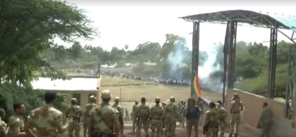 A screenshot from video posted to Facebook by Jawar Mohammed of the Irreecha stampede, in which security forces look on as people run away. Shots can be heard as smoke rises from the scene.