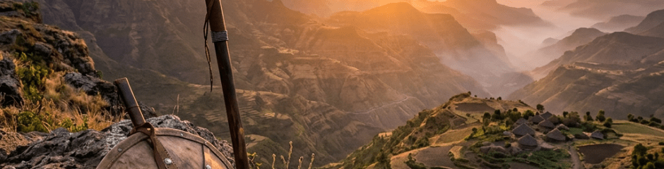 Traditional spear and shield beside rocky ledge with mountain village and sunset in background