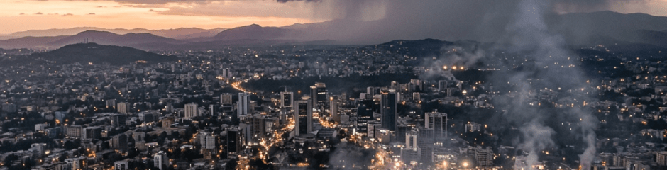 City skyline with tall buildings, roads, and dark storm clouds approaching